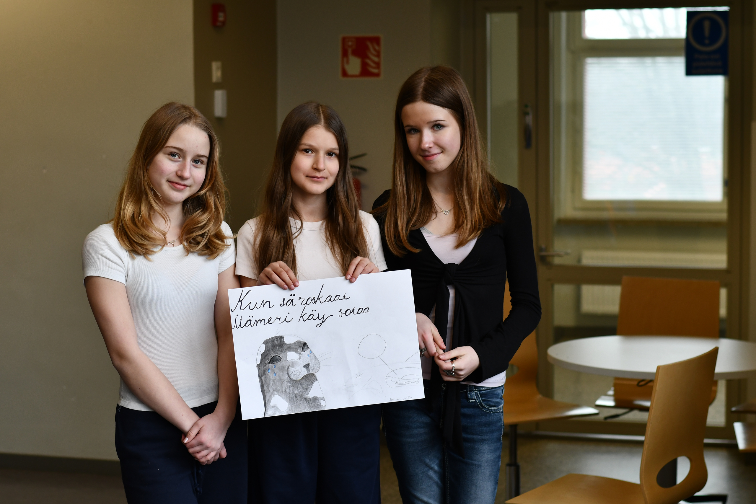 Aini, Siiri ja Alma poseeraavat julisteensa kanssa.