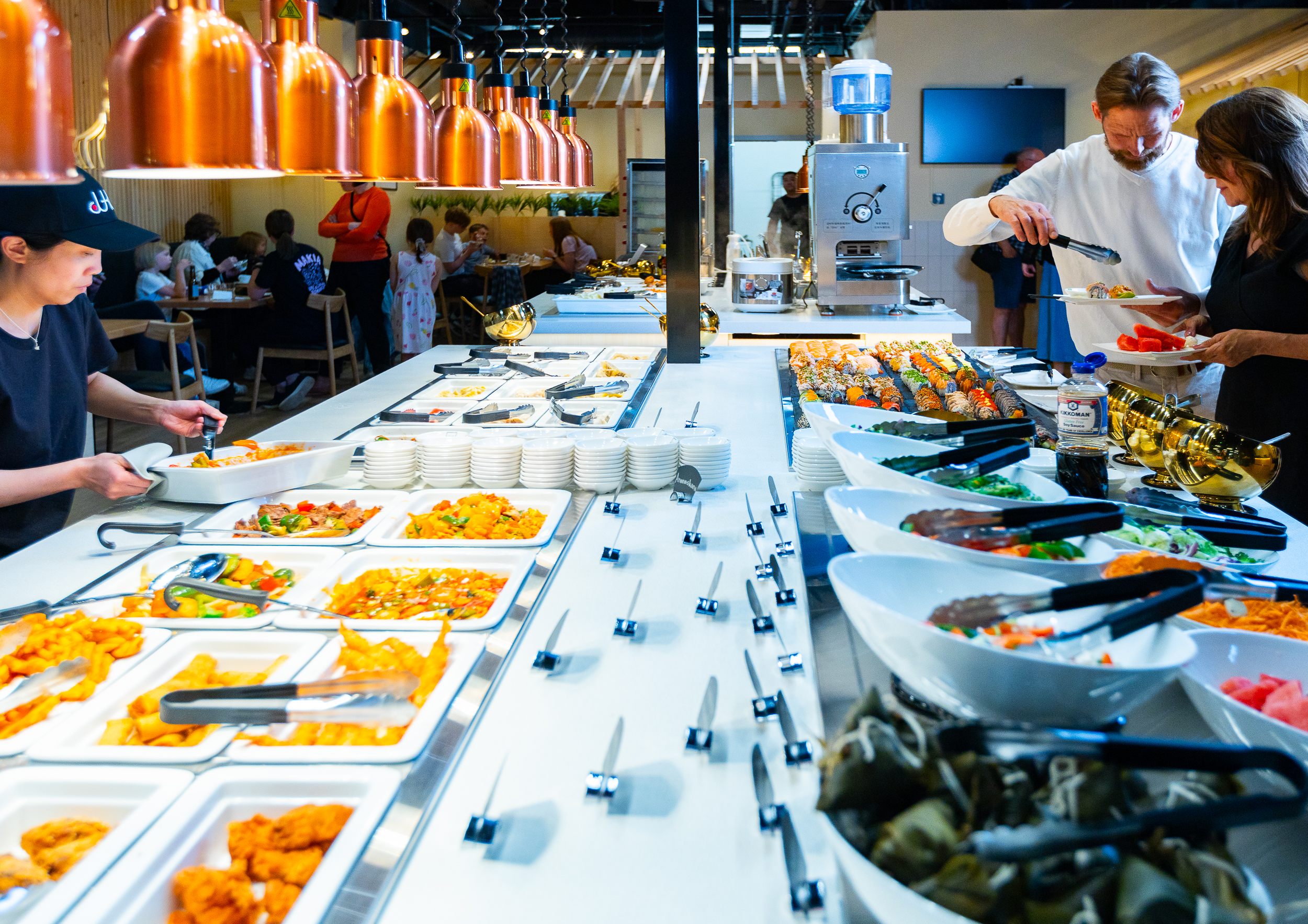 Kaksi buffetpöytää ja maistelutilaisuuden osallistujia Ravintola Juku Lippulaivassa