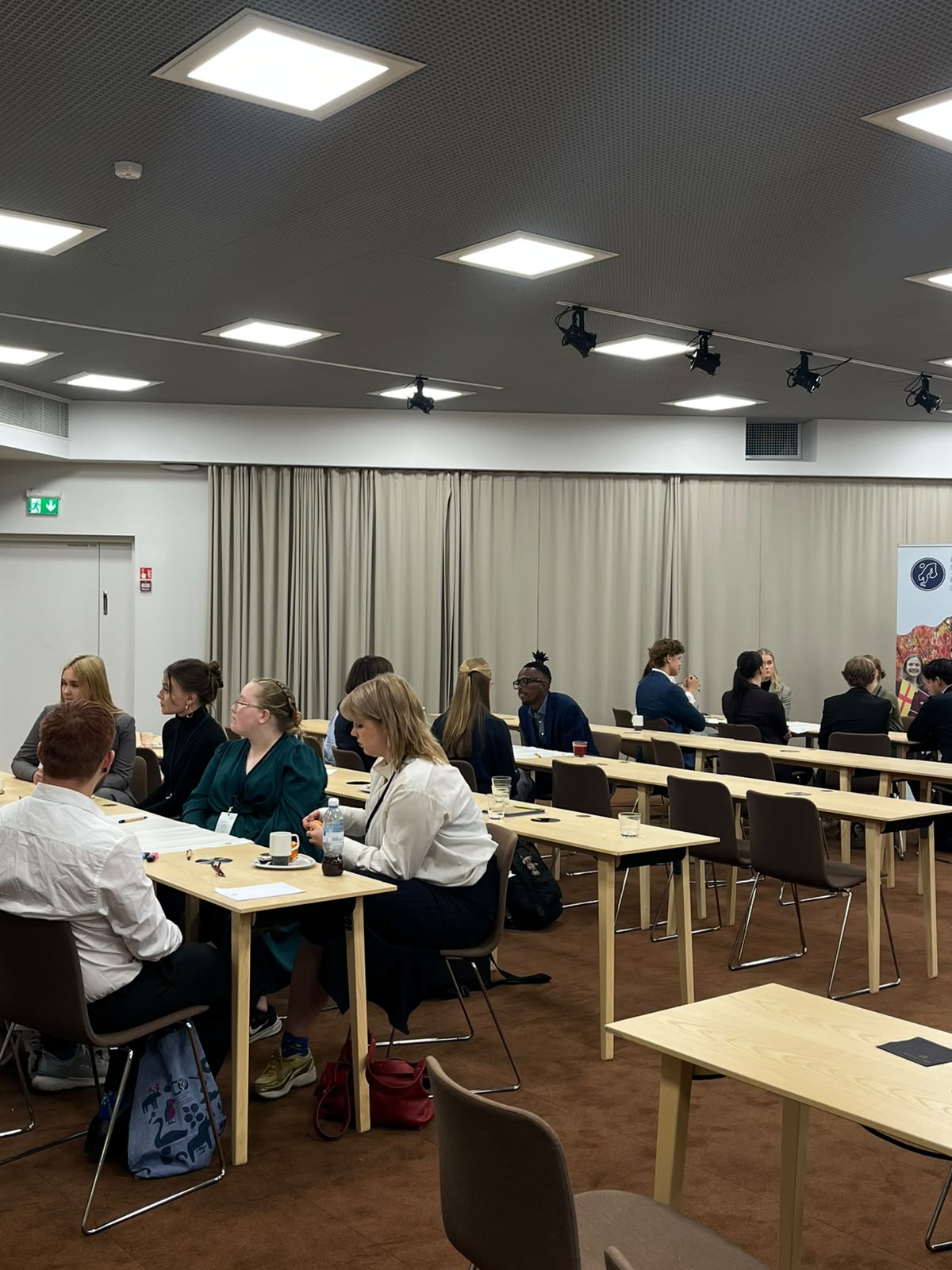 Foorumin osallistujia keskustelemassa pienryhmissä pöytien ääressä.