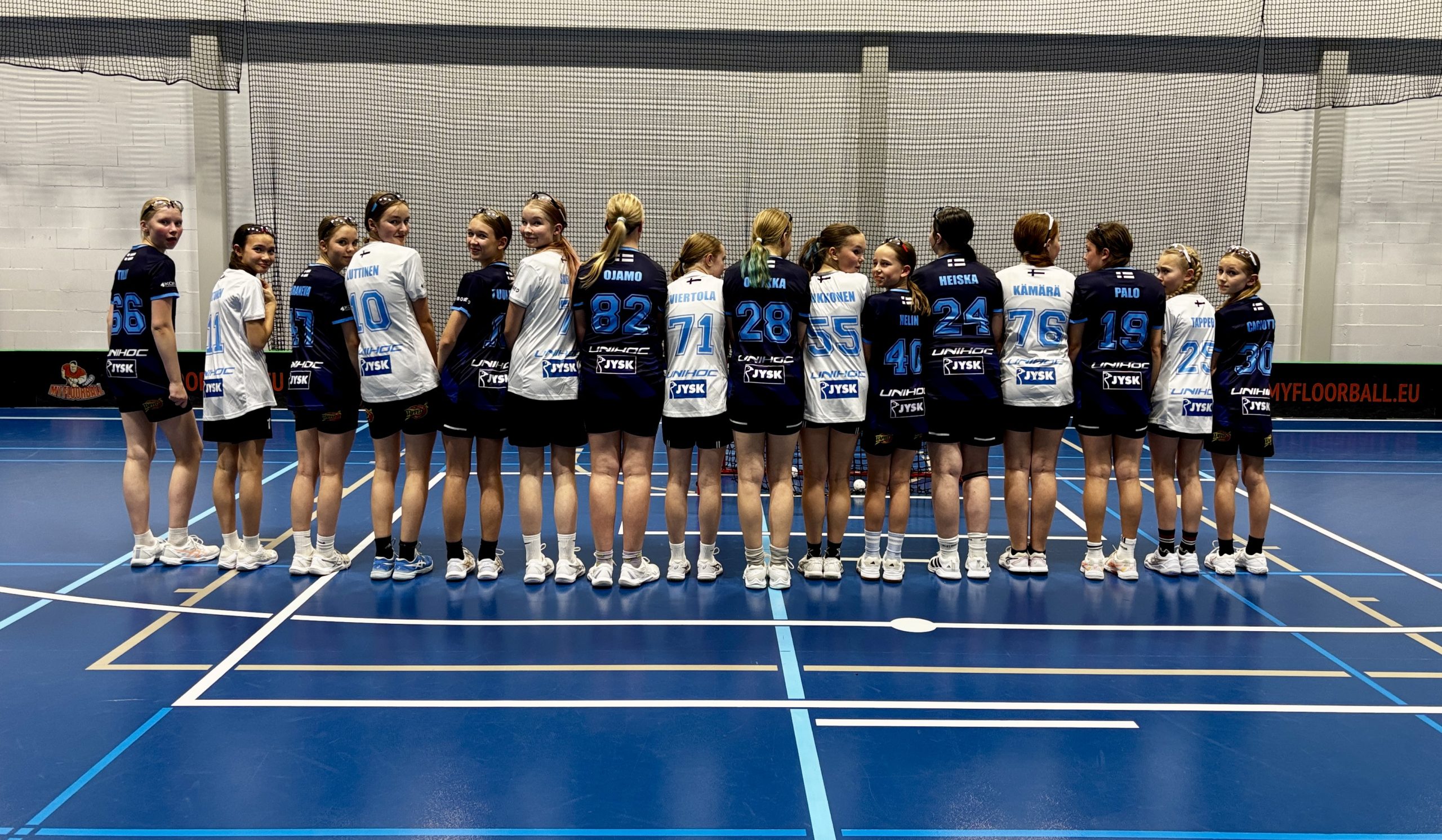 Northern Starsin U14-tyttöjoukkueen pelaajat seisovat rivissä salibandykentällä pelipaitojen selkäpuolet kameraan päin.